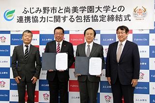 締結書を持った市長と男性、その両脇に男性が一人ずつ立っている写真