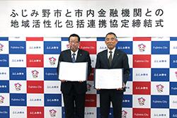 市長と茶色のネクタイを身に着けている市内金融機関代表の方が締結書を持って横並びで立っている写真