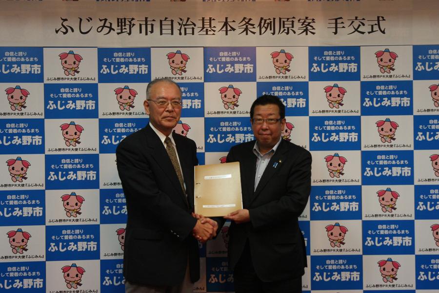 手交式で自治基本条例策定市民協議会代表の方と市長が握手をして記念撮影をしている写真