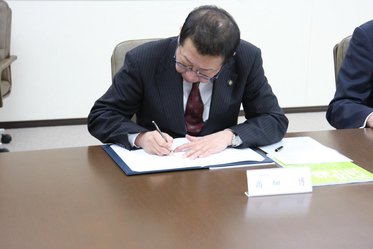 協定書に調印をしている市長の写真