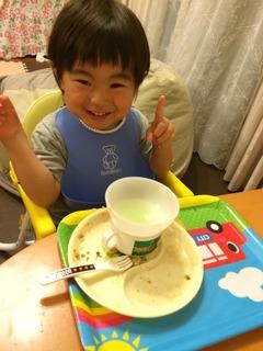 車のイラストが描かれたトレーに空になったお皿が置かれていて、赤ちゃんがピースをしている写真