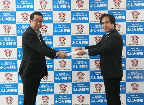 スーツを着た男性から市長に一次答申書を手渡している写真