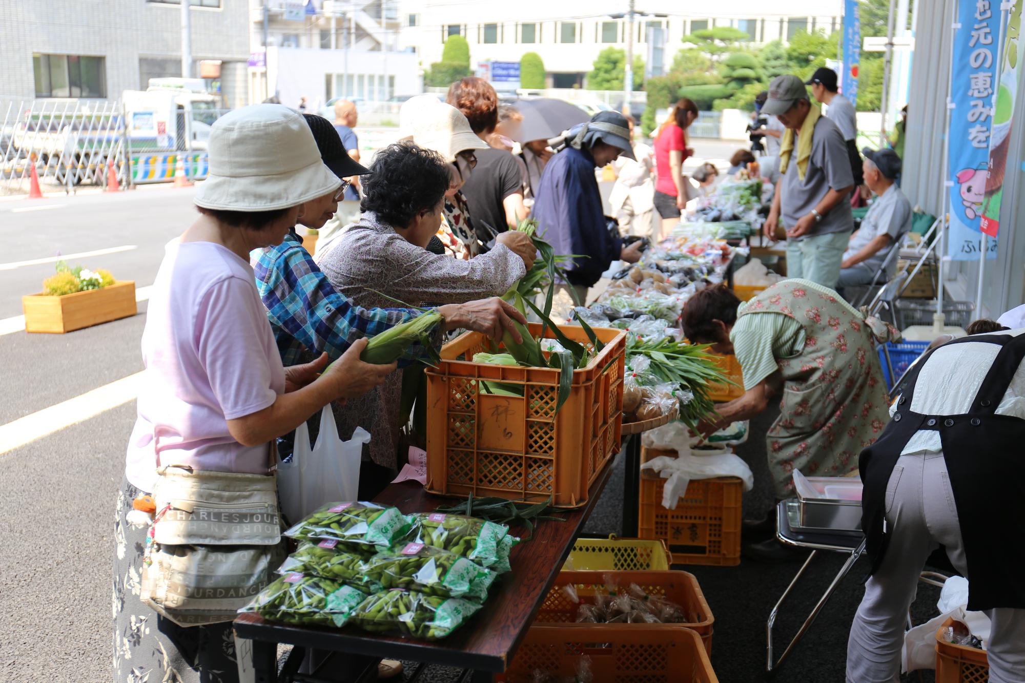 大勢の人が野菜を買いに集まっている写真