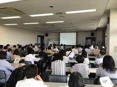 会議室にて、認知症サポーター養成講座に沢山参加されており、席に着いて講師の方の話を聞いている様子の写真