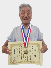シルバースポーツ大会でマグダーツの優勝をした男性が賞状とメダルを持っている