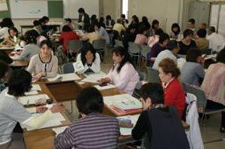 保健推進員定例会が行われており、各グループに分かれ、机に資料を広げて話し合いをしている様子の写真