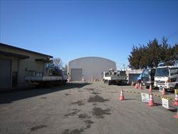 建物の向かい側には沢山の工事車両やトラックが止まっている大井清掃センター跡地の写真