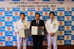 ホンダ学園の方と市長が協定書を手に持ち、関係者の男性と3人で写っている写真