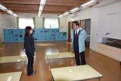 真新しい室内には右側には手洗い場が設置され、奥には水色の棚が置かれており、机が並べられている中央付近で、女性が市長と話をしている様子の写真