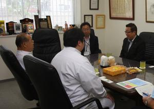 机に商品が置かれており、市長と藤澤ねぼけ堂の関係者の方々が話をしている写真
