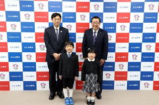 笑顔の市長と関係者の前に緊張した新1年生の男女が1人ずつ並んで記念写真