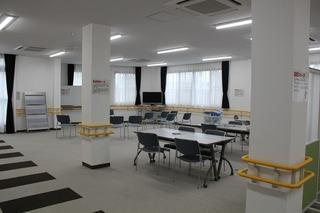 机といすが並べられた広いホールの写真