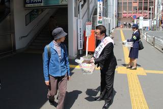 街頭で市長が市民に資料を配り、交通安全を呼びかけている写真