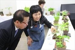 鉢植えの山野草を中腰になり見る、市長と女性の写真
