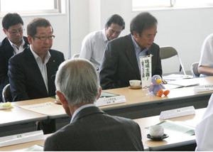 市長が机の上に資料を広げ、周りの関係者の方々も資料に目を通しながら、熱心に説明を聞いている写真