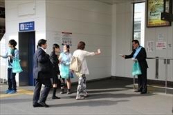 駅のホームに居る市民の方に、市長や参加者が緑の袋に入った「ごみのポイ捨て及び路上喫煙防止キャンペーン」のチラシを手渡ししている様子の写真