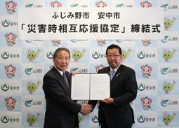 「ふじみ野市安中市災害時相互応援協定」締結式の横断幕の前で、安中市長とふじみ野市長が安中市防災協定書を持って、握手をしている写真