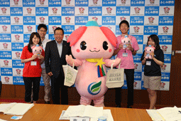 中央にふじみん、その左側に市長、職員の男性、赤色のシャツを着てふじみんのぬいぐるみを持った女性、右側にピンク色のシャツを着てふじみんのぬいぐるみを持った男性、ふじみんのぬいぐるみを持った職員の女性が笑顔で写っている写真