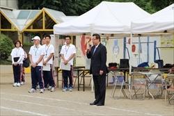 大会関係者がテントの前に整列して市長の話しを聞いている写真