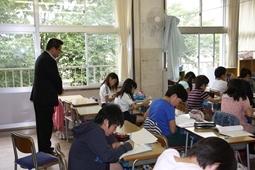 教室にて、児童がプリントに文字を書き込んでおり、その様子を市長が後ろからみている写真