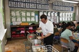 教室に置かれている鍋からおかわりをしている市長の写真