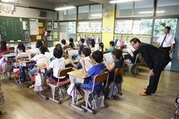授業を受けている生徒達の後ろから教科書をのぞき込む市長の写真