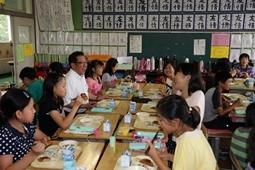 机を向かい合わせに並べ、その中に市長も入り女の子たちとしゃべりながら給食を楽しんでいる市長の写真