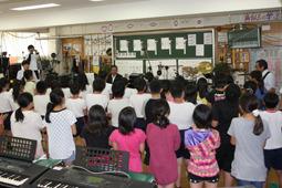 市長の周りでバンド演奏をする先生方とその演奏を聞いている生徒達の写真