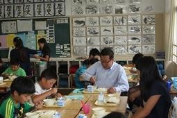 グループごとに分かれて座り、その中に市長も一緒に給食のカレーを食べている写真
