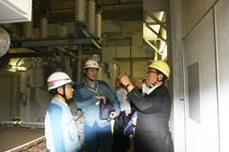 黄色のヘルメット姿の市長に2名の関係者の人が変電所の説明をしている写真
