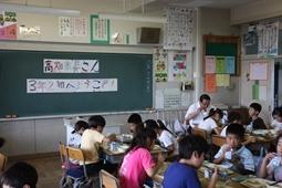 子供達と給食を食べている市長を教室の左後方斜めから全体を写した写真