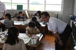 各机で絵を描いている児童に腰を低くして言葉をかけている市長の写真