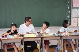 市長が給食を食べながら隣の児童と話をしている写真