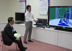 テレビに映し出された映像を見ながら、市長が白いワイシャツの男性より説明を受けている写真