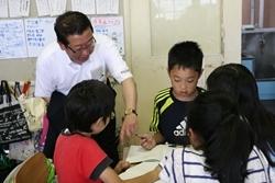 亀久保小学校にてグループで話し合っている生徒に話しかける市長の写真