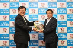 市長たちが市民便利帳(タウンページ合冊版)を手に持ち記念撮影している写真