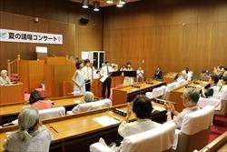 議場コンサートで、中央に立つ女性に拍手をする観客の写真