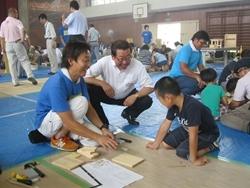 ものづくりくらぶの会場で、作業する親子に市長が話しかけている写真