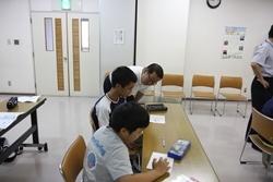 席に座っている男の子2名が学習している横で体をかがめて見ている市長の写真