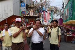 市長と黄色のシャツを着た男性達がみこしを担いでいる写真