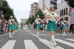 指揮棒をもって行進する、マーチングバンドの女性の写真