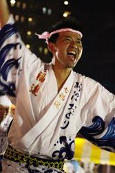 法被を着て、頭に手拭いを巻いた男性が踊っている写真