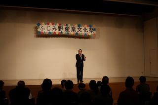 「ふじみ野産業文化祭」の横断幕が掲げられた舞台の上で市長がマイクを持って話をしている写真