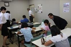 勉強している学生の横に立つ関係者や、女の子の横で中腰になり、のぞき込む市長の写真