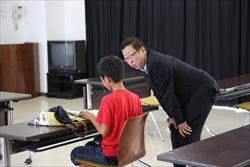 赤いシャツを着た男の子の横で、中腰になり、話をしている市長の写真