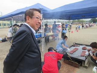 テントの下に、大きな鉄板がおかれ、肉のようなものが焼かれており、その様子を市長が見ている写真