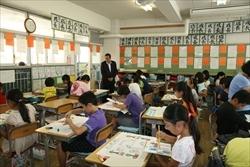 絵具を使い、色を塗る生徒の様子を見ている市長の写真