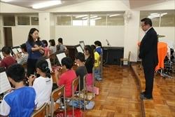 リコーダーを吹く三角小学校の生徒を、後ろから見ている市長の写真