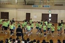 黄緑色のシャツを着た、三角小学校の3年1組の生徒が、市長の前で飛び跳ねている写真