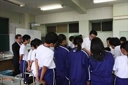 生徒と、市長が、中央に立つ男性の周りに集まり注目している写真